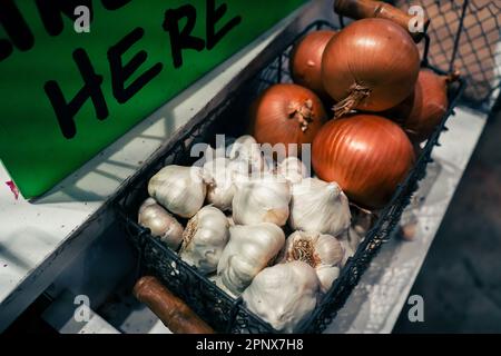 Knoblauchzehen und gelbe Zwiebeln in einem Korb Stockfoto