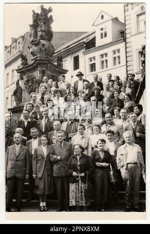 Vintage-Gruppenporträt von Menschen, die sich auf Stufen vor einem Denkmal und Gebäuden versammelten. Eine große, vielfältige Gruppe von Männern und Frauen, die in formellen Anzügen gekleidet sind Stockfoto