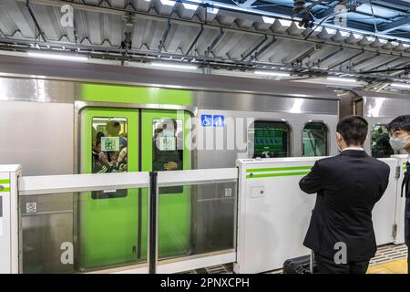 April 2023 die Zugkutsche von Tokio kommt am Bahnsteig an, der Zug ist voll mit Pendlern, Japan, Asien Stockfoto