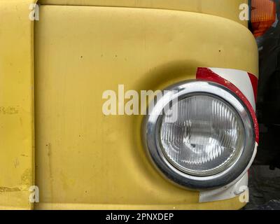 Detaildarstellung des runden Scheinwerfers eines gelben IFA W50-Lkws, der in der Deutschen Demokratischen Republik hergestellt wurde. Stockfoto