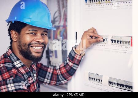 Schwarzer Mann im Hochformat, Elektriker und Sicherungskasten für Strom, Stromversorgung mit Wartung des Hauptleistungsschalters prüfen. Ingenieur, Techniker und Stockfoto