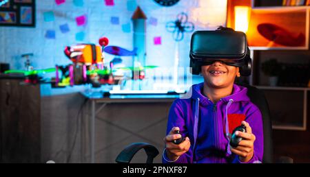 Intelligentes indisches Kind, das die Drohne steuert, indem es zu Hause VR- oder Virtual-Reality-Headset und Controller trägt – Konzept moderner Technologie, futuristisch Stockfoto