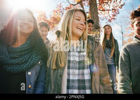 Freunde machen glückliche Zeiten noch glücklicher. Eine Gruppe von Freunden im Teenageralter, die gemeinsam einen Herbsttag im Freien genießen. Stockfoto