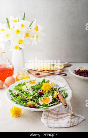 Löwenzahnsalat mit Eiern, Kartoffeln und Bohnen auf hellem Tischhintergrund Stockfoto