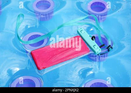 Wasserdichte, transparente Plastikabdeckung für ein Mobiltelefon oder Mobiltelefon über einer aufblasbaren Pool-Matratze Stockfoto