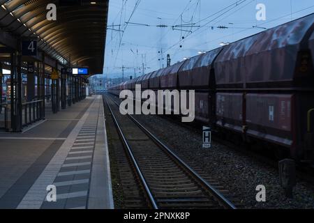 Kaiserslautern, Deutschland. 21. April 2023. Güterzug, der bei landesweiten Streiks neben einem leeren Bahnsteig vorbeifährt. Der Streik wurde von der EVG-Eisenbahn- und Verkehrsgewerkschaft nach gescheiterten Lohnverhandlungen mit dem Eisenbahnunternehmen Deutsche Bahn (DB) eingeleitet. Die Gewerkschaftsmitglieder wurden aufgefordert, am Freitag zwischen 3 und 11 Uhr alle Bahnverbindungen anzuhalten Kredit: Gustav Zygmund/Alamy News Stockfoto