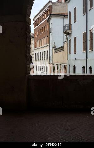 Kanal, der von einem Gebäude umgeben ist, das von Bögen einer überdachten Veranda in einer italienischen Stadt eingerahmt ist Stockfoto