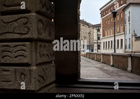 Kanal, der von einem Gebäude umgeben ist, das von Bögen einer überdachten Veranda in einer italienischen Stadt eingerahmt ist Stockfoto