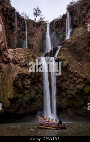 Ein Mann nähert sich dem Fuß der Ouzoud Falls mit einem Boot. Stockfoto