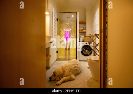 Hund mit einer Frau im Badezimmer Stockfoto