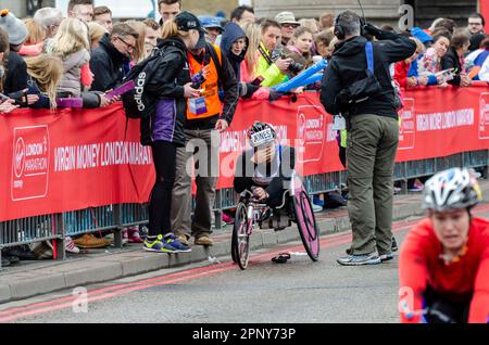 Hilfe für den Rollstuhlsportler Jade Jones nach einem Halt beim Virgin Money London Marathon 2015 auf der Tower Bridge, Großbritannien. Marshal und Medien Stockfoto