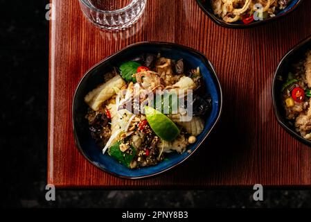 Gebratener chinesischer Reis mit Tintenfisch, Gemüse und Kräutern. Restaurant Stockfoto