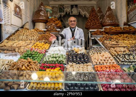 Konditorin, der typische marokkanische Süßigkeiten in einem Verkaufsstand in der Medina von Marrakesch verkauft. Stockfoto