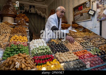 Konditorin, der typische marokkanische Süßigkeiten in einem Verkaufsstand in der Medina von Marrakesch verkauft. Stockfoto