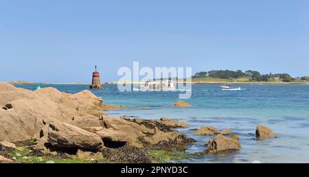 Blick auf den felsigen Strand mit Booten und Leuchtturm im Hintergrund in aber Benoit, Bretagne-Frankreich Stockfoto