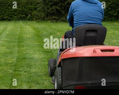 Ein Mann mäht den Rasen mit einem Aufsitzmäher. Stockfoto