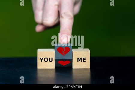 Symbol zum Aufbrechen einer Beziehung. Die Hand verwandelt einen hölzernen Würfel und verwandelt ein Herzsymbol in ein Symbol für gebrochenes Herz. Stockfoto