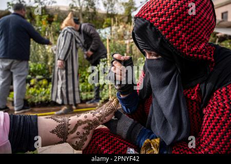 Muslimische Frau, die den Fuß eines Klienten mit Henna dekoriert, auf dem Platz Jemaa el-Fnaa in Marrakesch. Stockfoto