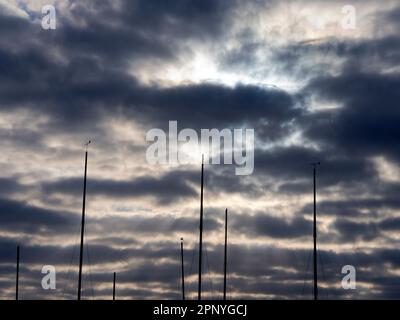 Dunkler, bedeckter Himmel; eine abstrakte Reihe von Yachtmasten und -Takelings bei Sonnenaufgang in Abingdon Marina an der Themse. Stockfoto