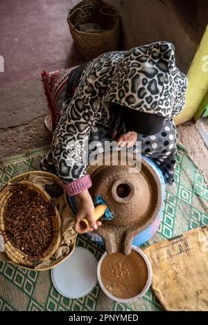 Berber-Lady, die Arganpaste mit einer manuellen Steinschleifmaschine herstellt. Stockfoto