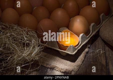 Frisch gepflückte Hühnereier auf rustikalem Hintergrund. Hühnereier in Heu, ländliche Szene Stockfoto