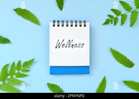 Wellnesskonzept. Ein Wort auf blauem Notizblock. Schöne minimalistische flache Lagezusammensetzung. Stockfoto