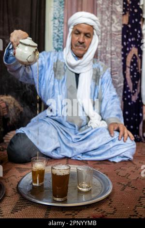 Touareg macht Tee auf dem Boden auf einem Teppich. Stockfoto