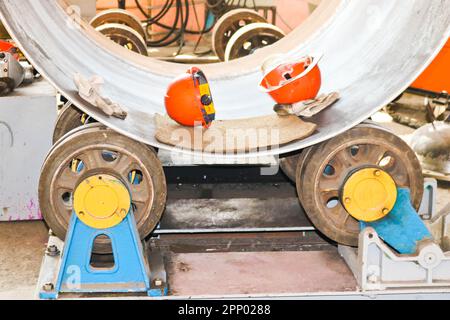 Das Verfahren zur Herstellung eines zylindrischen Behälterkörpers, eines Wärmetauschers auf Rollen, durch Walzen, Schweißen und orangefarbene Helme in der Industrie p Stockfoto