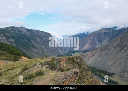 Blick vom Katu-Yaryk Pass zum Chulyshman-Tal. Hohe Berge, ein Fluss und darunter. Sommersaison im Altai-Gebirge Stockfoto