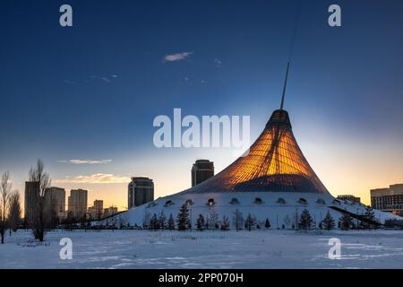 Astana, Kasachstan - 20. Januar 2023: Der Sonnenuntergang beleuchtet das durchsichtige Dach von Khan Shatyr, dem größten Einkaufs- und Unterhaltungszentrum in Astana Stockfoto