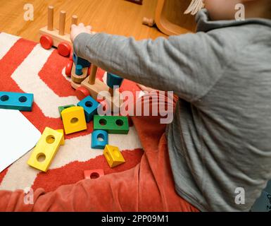 Blick von oben auf das Kinderzimmer - der Boden eines hellen und lebendigen Kinderzimmers, spielend mit einer Auswahl an bunten Holzspielzeugen. Stockfoto