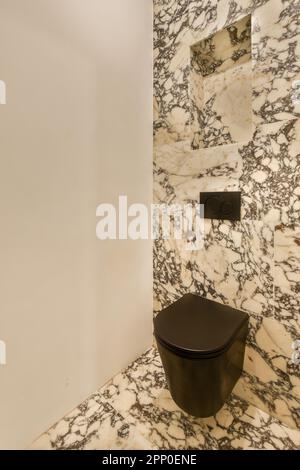 Ein Badezimmer mit Marmorwänden und schwarzer Toilette in der Ecke, obwohl es für die öffentliche Nutzung zu benutzen scheint Stockfoto