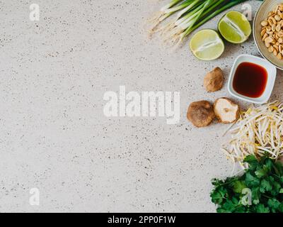 Kochzutaten für asiatische Gerichte: Shiitake-Pilze, Sprossen, Koriander, Limette und Knoblauch auf grauem Betonhintergrund, Draufsicht Stockfoto