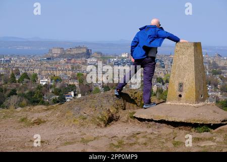 Edinburgh, Schottland, Großbritannien. 21. April 2023 Starke, bläuliche Winde auf dem Gipfel des Blackford Hill, bei denen die Besucher ihr Gleichgewicht im Wind nicht halten können. Blick über die Dächer der Stadt in Richtung Edinburgh Castle. Kredit: Craig Brown/Alamy Live News Stockfoto