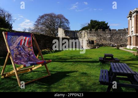 Riesiger Holzstuhl mit Wikingerfiguren neben hölzernen Gartenmöbeln mit St. Ruinen von Mary's Abbey im Hintergrund, York, Großbritannien. Stockfoto