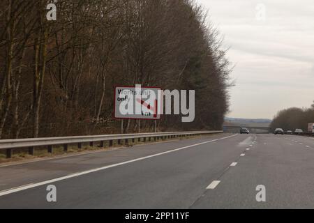 Ein scheinbar normales Straßenschild, das die Fahrer über eine Abzweigung einer Arbeitseinheit informiert, die eine Meile vor uns liegt. Stockfoto