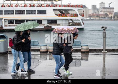 Während des starken Regens in Istanbul wurden Menschen mit Sonnenschirmen gesehen, um sich vor Regen im und um das Kadikoy-Dock zu schützen. Stockfoto