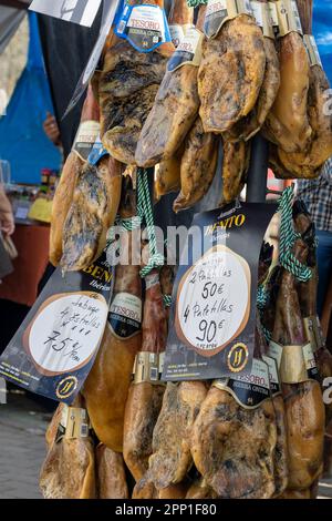 ALCOUTIM, PORTUGAL: 25. MÄRZ 2023: Jamon-Schweinebeinen, ein traditioneller spanischer Schinken, der auf einem Festival verkauft wird. Stockfoto