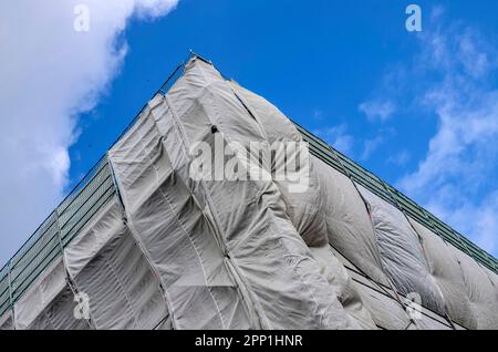 Abgewinkelte Nahaufnahme von Gerüsten und Schutzüberzug auf einer hohen Baustelle Stockfoto