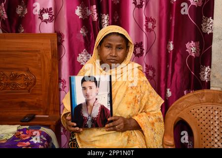 ReNu Begum (55) posiert für ein Porträt mit einem Foto ihres verstorbenen Sohnes Robiul Islam Manik. Vor zehn Jahren am 24. April 2013 wurde die Welt Zeuge einer der schlimmsten Industriekatastrophen der Geschichte, als das Rana Plaza-Gebäude in Bangladesch zusammenbrach, mehr als 1.100 Menschen tötete und 2500 weitere verletzte. Die Tragödie hat weltweit Schockwellen ausgelöst und Sorgen über die unsicheren Arbeitsbedingungen im boomenden RMG-Sektor (Ready-Made Garment) in Bangladesch ausgelöst. In dem achtstöckigen Gebäude waren mehrere Fabriken untergebracht, in denen Kleidung für globale Marken wie Primark, Mango und Benetton hergestellt wurde. Das Buildin Stockfoto