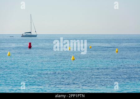 Segelboot, das vor der Küste von Ses Illetes in Mallorca mit Bojen im Wasser segelt Stockfoto