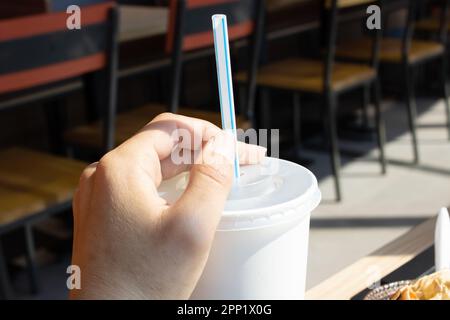 Weißer Kunststoffbecher und Strohhalm in der Hand, Nahaufnahme Stockfoto