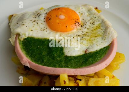 Gebratenes Ei auf Spinat in einer Wurstschüssel und gebratene Kartoffeln nach österreichischer Art Stockfoto