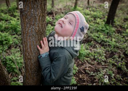 Umarmen eines Baumes: Das Mädchen fühlt sich ruhig und harmonisch und genießt eine Waldtherapie, die das Soul Tree-Therapiekonzept Shinrin-Yoku neu aufbaut. Stockfoto