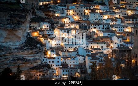 Blick auf einen Teil der Altstadt von Alcala del Jucar in Albacete, Castilla La Mancha, Spanien, mit weißen Häusern, die bei Sonnenaufgang von Straßenlaternen beleuchtet werden Stockfoto