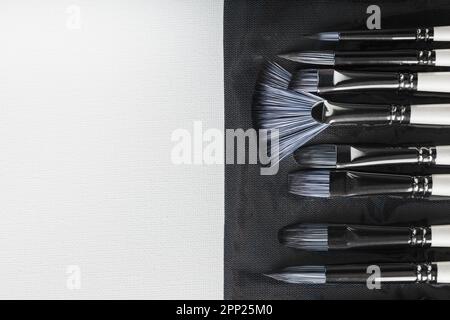 Pinsel, Palettenmesser in einem Federmäppchen auf weißem Leinenhintergrund. Draufsicht mit freiem Platz Stockfoto