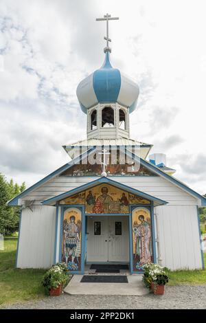 Die blau-weiß gestreifte Zwiebelkuppel und der kunstvoll verzierte Eingang der Russisch-orthodoxen Nikolaikirche in Nikolaevsk, Alaska. Die hölzerne Kirche wurde von russischen Migranten der Sekte der Alten Gläubigen erbaut, die im 17. Jahrhundert vor religiöser Verfolgung flohen Stockfoto