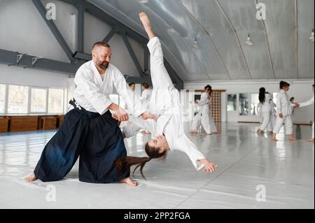 Aikido-Lehrer und Schüler, die Wurf- und Sturztraining betreiben Stockfoto