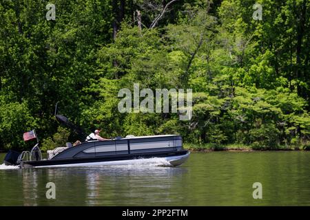 Mann und Hund auf einem Pontonboot Genießen Sie den Sommertag auf dem See. Pontonparty mit dem Boot auf dem Süßwassersee. Stockfoto