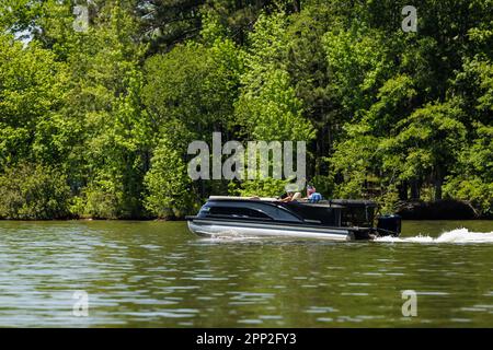 Bootsfahrer auf einem Pontonboot genießen den Sommertag auf dem See. Pontonparty mit dem Boot auf dem Süßwassersee. Stockfoto